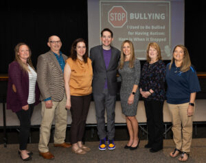 Six people pose for a photograph with presenter Dr. Kerry Magro, center.
