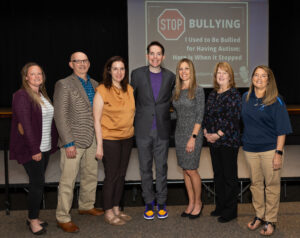 Six people pose for a photograph with presenter Dr. Kerry Magro, center.